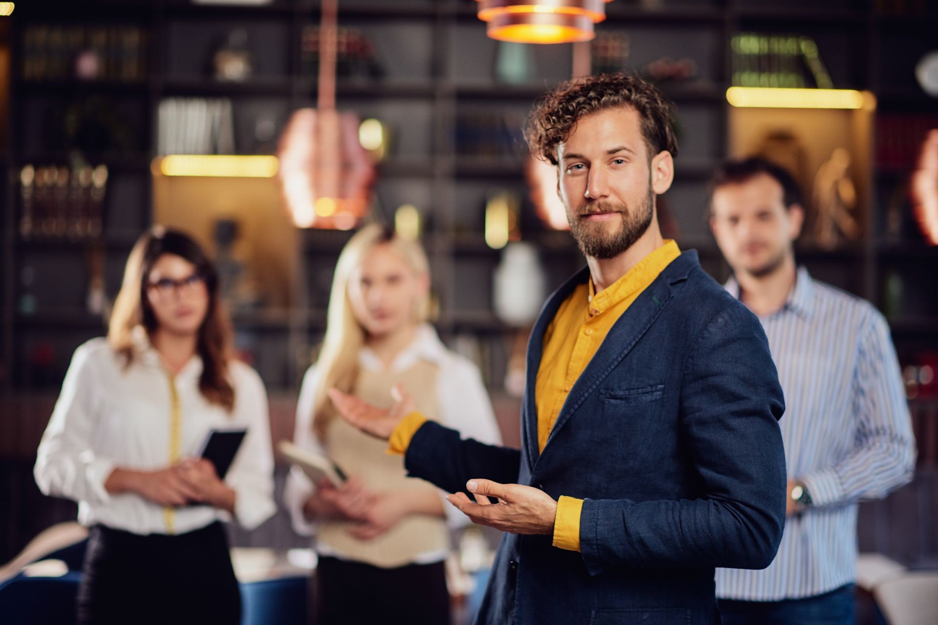 Portrait of young bearded Caucasian businessman dressed smart casual posing with his successful team in restaurant.